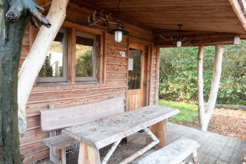 Houten lodge met rustieke bank en tafel op de veranda bij Nature Lodge op De Wije Werelt, Nederland.