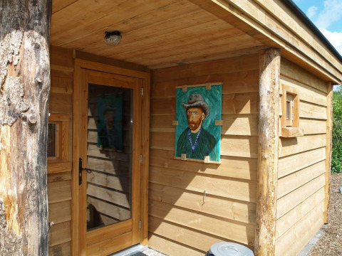 Entrada de una pequeña casa de madera con retrato de Van Gogh en la pared en De Wije Werelt, Países Bajos.