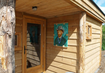 Entrée d'une petite maison en bois avec un portrait de Van Gogh sur le mur à De Wije Werelt, Pays-Bas.