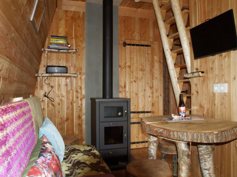 Acogedor interior de la tiny house Van Gogh en De Wije Werelt, Países Bajos, con estufa de leña y muebles rústicos.