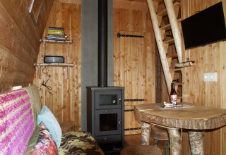 Knusse inrichting van het Van Gogh tiny house bij De Wije Werelt in Nederland, met houtstoof en houten meubelen.