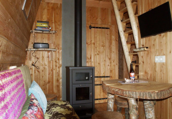 Hyggelig indretning af Van Gogh tiny house på De Wije Werelt, Nederlandene, med træmøbler og brændeovn.