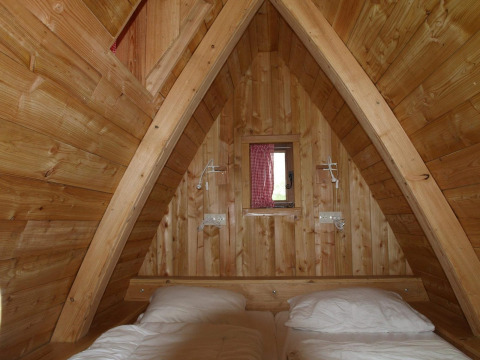 Interieur van de tiny house Van Gogh bij De Wije Werelt in Nederland, met houten afwerking en bed.
