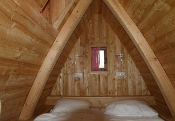 Vue intérieure de la tiny house Van Gogh à De Wije Werelt aux Pays-Bas, avec murs en bois et lit confortable.