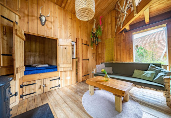 Indvendig udsigt af en hyggelig træhytte på Nature Lodge ved De Wije Werelt i Holland med sofa og seng.