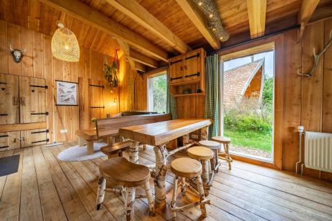 Intérieur d’un lodge en bois chaleureux avec grandes fenêtres à Nature Lodge à De Wije Werelt, Pays-Bas.