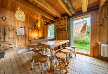 Intérieur d’un lodge en bois chaleureux avec grandes fenêtres à Nature Lodge à De Wije Werelt, Pays-Bas.