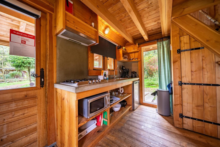 Keuken met houten interieur in Nature Lodge op De Wije Werelt, Nederland, met fornuis en tuinzicht.