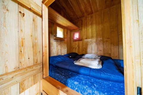Acogedor dormitorio con paredes de madera y cama doble en Nature Lodge de De Wije Werelt, Países Bajos.