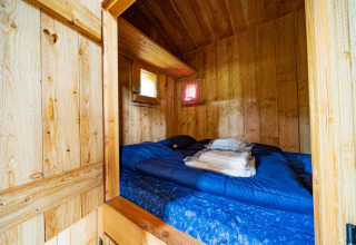 Acogedor dormitorio con paredes de madera y cama doble en Nature Lodge de De Wije Werelt, Países Bajos.