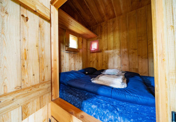 Chambre douillette avec murs en bois et lit double à Nature Lodge de De Wije Werelt, Pays-Bas.