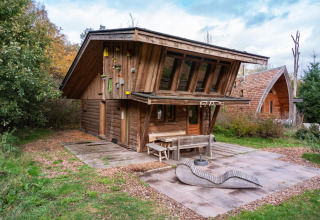 Capanna di legno al Nature Lodge di De Wije Werelt, Paesi Bassi, circondata da alberi e zona esterna.