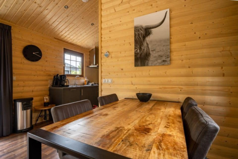 Interno della lodge Boekhorst a De Wije Werelt, Paesi Bassi, con pareti in legno e tavolo da pranzo.