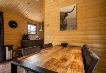 Interior de cabaña Boekhorst en De Wije Werelt, Países Bajos, con paredes de madera y mesa de comedor.