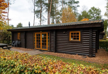 A cozy log cabin at Boekhorst in De Wije Werelt, Netherlands, surrounded by autumn trees and foliage.
