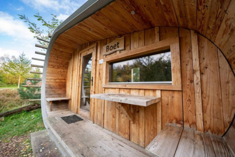 Exterior de la tiny house Boet en De Wije Werelt, Países Bajos, con revestimiento de madera y vista natural.