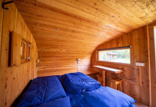Intérieur de la tiny house Boet à De Wije Werelt aux Pays-Bas, avec des panneaux bois et des draps bleus.