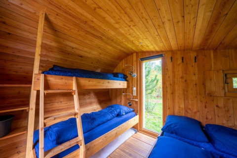 Interior de la tiny house Boet en De Wije Werelt, Países Bajos, con literas y paredes de madera.