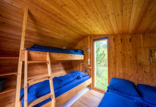 Interior de la tiny house Boet en De Wije Werelt, Países Bajos, con literas y paredes de madera.