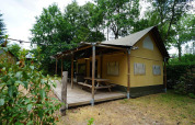 Safari glamping tent at De Wije Werelt in the Netherlands, surrounded by trees, with a wooden deck.