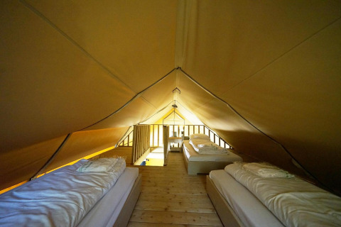 Innenansicht eines Safari-Glampingzelts mit drei Einzelbetten in De Wije Werelt, Niederlande.