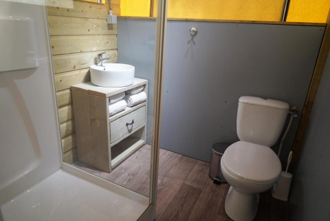 Salle de bain de la Glampingtent à De Wije Werelt, Pays-Bas, avec douche, lavabo, toilettes et bois.