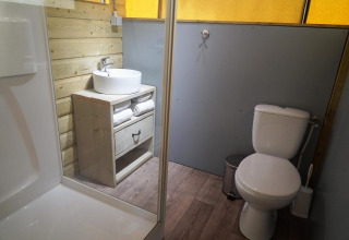 Baño en Glampingtent de De Wije Werelt, Países Bajos, con ducha, lavabo, inodoro y decoración de madera.