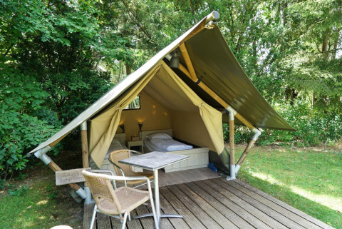 Mini-Glamping-Zelt bei De Wije Werelt in den Niederlanden, mit Terrasse, Tisch und Stühlen im Grünen.