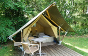 Mini glamping telt ved De Wije Werelt i Holland med trædæk, udendørs borde og stole omringet af natur.