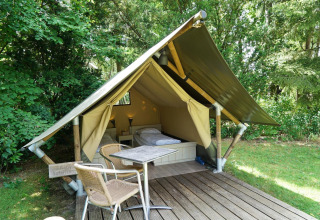 Mini tenda glamping a De Wije Werelt nei Paesi Bassi, con terrazza, tavolo, sedie e circondata dal verde.