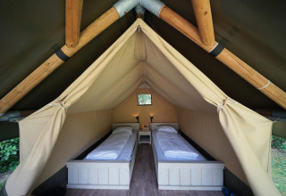 Interieur van een Mini glamping tent bij De Wije Werelt in Nederland, met twee eenpersoonsbedden en zachte verlichting.