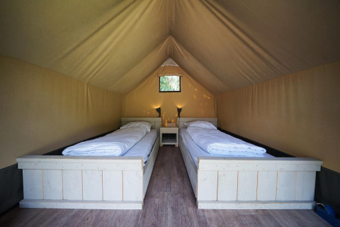 Innenansicht eines Mini-Glampingzelts bei De Wije Werelt in den Niederlanden mit zwei Einzelbetten.