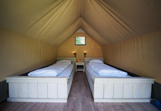 Interno di una mini tenda safari glamping a De Wije Werelt nei Paesi Bassi con due letti singoli.