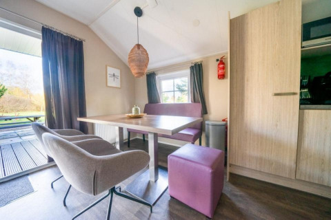 Moderne spiseplads i Boslodge på De Wije Werelt, Holland, med lilla siddepladser og udsigt til naturen.