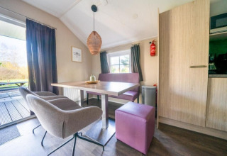 Comedor moderno en Boslodge de De Wije Werelt, Países Bajos, con asientos morados y vista al exterior.