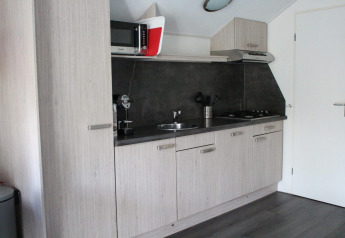 Moderne Küchenzeile in der Boslodge bei De Wije Werelt, Niederlande, mit Holzmöbeln und Geräten.