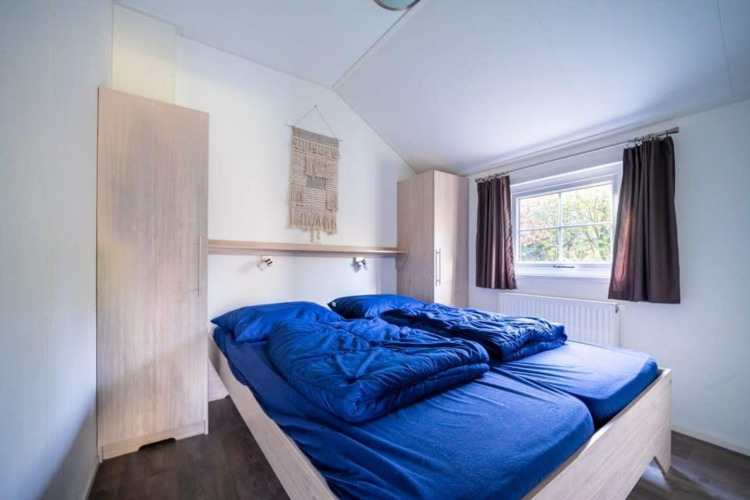 Dormitorio en Boslodge en De Wije Werelt, Países Bajos, con ropa de cama azul y armarios empotrados.