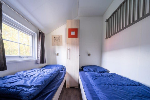 Værelse på Boslodge ved De Wije Werelt i Holland med to enkeltsenge, blå sengetøj og stort vindue.