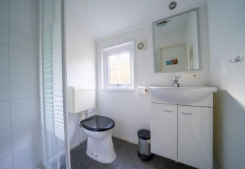 Et lyst og moderne badeværelse på Boslodge ved De Wije Werelt i Holland med toilet, håndvask og bruser.