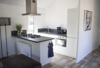 Cuisine blanche moderne avec plan de travail noir au Velthorst, De Wije Werelt, Pays-Bas, décorée d’un tableau.