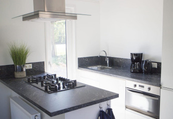 Cuisine moderne avec plan de travail noir, gazinière, four et cafetière à Velthorst, De Wije Werelt.