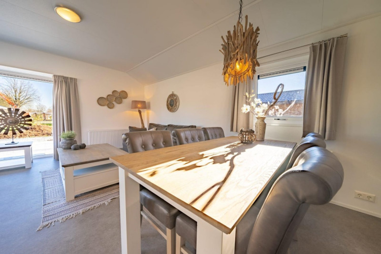 Luminoso comedor y sala en una cabaña Velthorst de De Wije Werelt, Países Bajos, con decoración de madera.