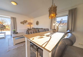 Luminoso comedor y sala en una cabaña Velthorst de De Wije Werelt, Países Bajos, con decoración de madera.