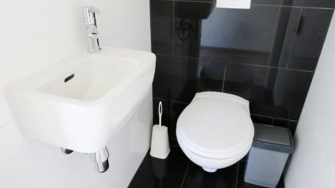 Baño moderno en Velthorst lodge en De Wije Werelt, Países Bajos, con lavabo, inodoro y cubo de basura.