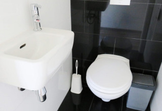 Baño moderno en Velthorst lodge en De Wije Werelt, Países Bajos, con lavabo, inodoro y cubo de basura.
