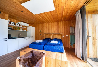 Indbydende lodge hos Fred på De Wije Werelt i Holland med træinteriør, dobbeltseng og køkken.