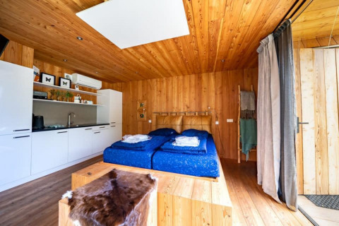 Lodge chaleureux Fred à De Wije Werelt aux Pays-Bas avec intérieur en bois, lit double et kitchenette.