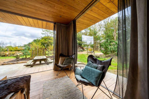 Vue depuis le lodge Fred à De Wije Werelt, Pays-Bas, avec des fauteuils confortables et nature paisible.