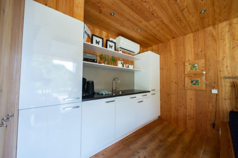 Kitchenette moderne avec meubles blancs et murs en bois au lodge Fred à De Wije Werelt, aux Pays-Bas.