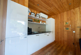 Cocina moderna con gabinetes blancos y paredes de madera en la cabaña Fred en De Wije Werelt, Países Bajos.